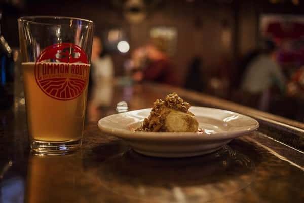 Menu item on a plate with a pint of beer on the bar top.