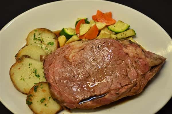 Cooked steak served with mixed vegetables and herb roasted potatoes.