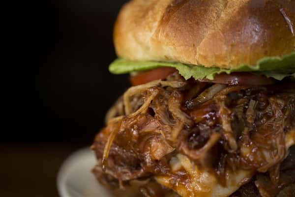 Close up of cheese burger with caramelized onions, lettuce, and tomato.