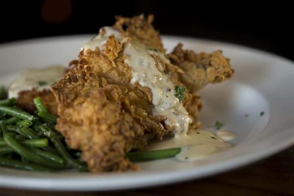 Fried chicken topped with Boursin cheese cream sauce served with a side of green beans.