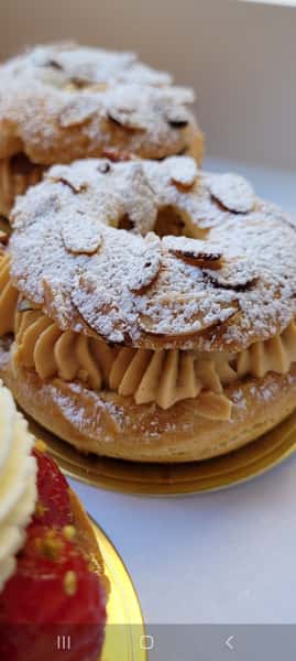 Paris-Brest pastry dusted with powdered sugar and sliced almonds, filled with piped praline cream