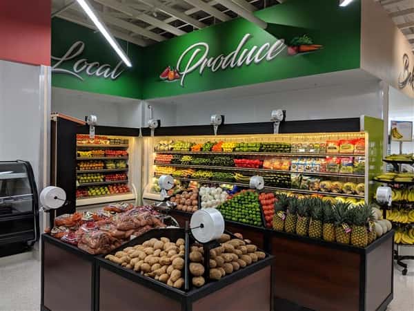 Produce section showing pineapples, tomatoes, onions, limes, apples, peppers and other fruits and vegetables