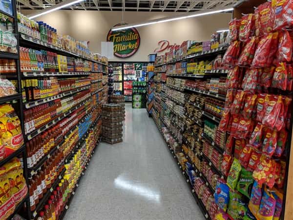 Market aisle with assorted hot sauces, canned goods, candy, sauces, beans
