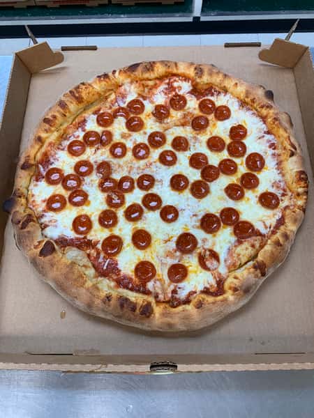 Large pepperoni pizza with melted mozzarella and a charred, golden crust in an open cardboard box.