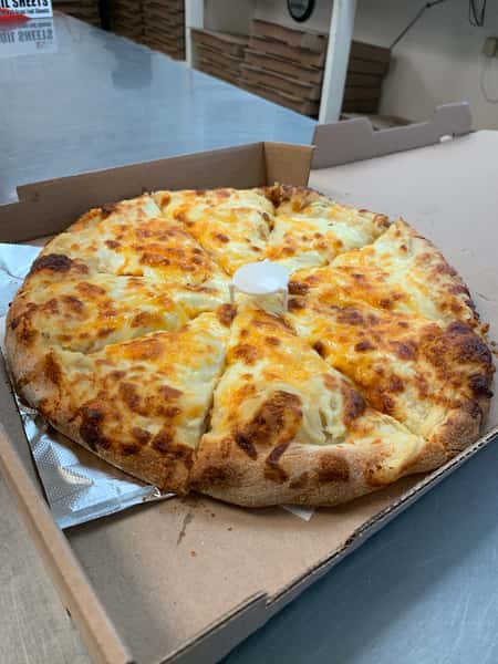 Thick, cheese-covered pizza cut into slices in an open cardboard box, with a pizza saver in the center.