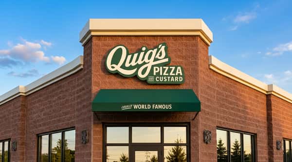 Quig's Pizza and Custard sign on a red brick building with a green awning against a blue sky.