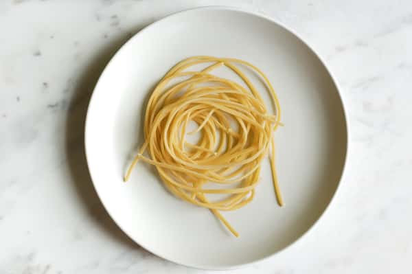 A small portion of plain cooked spaghetti (or linguine) neatly twirled and served on a plate without any sauce or toppings.