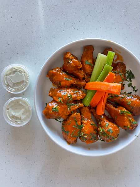 Buffalo chicken wings coated in spicy sauce, served with celery, carrots, and dipping sauce