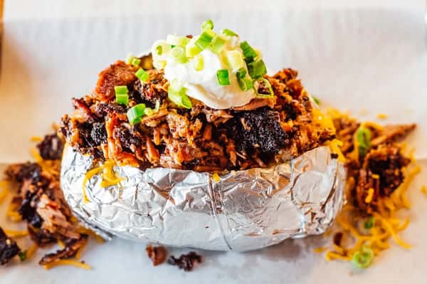 Loaded baked potato with BBQ meat, cheese, and toppings at Fainmous BBQ Pearland TX