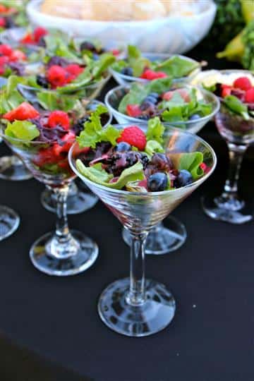 an assortment of fruit salads in martini glasses