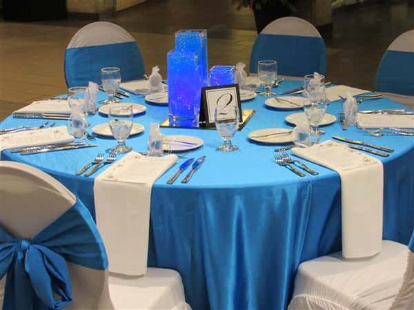 Round table set in light blue linen and decorated in blue details for an event