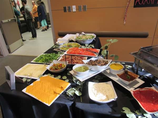Buffet tables covered in dark linen with a variety of platters and catering equipment ready for service