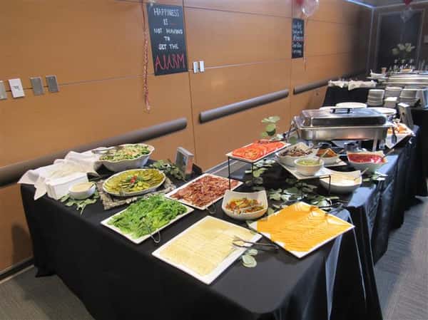 Buffet tables covered in dark linen with a variety of platters and catering equipment ready for service