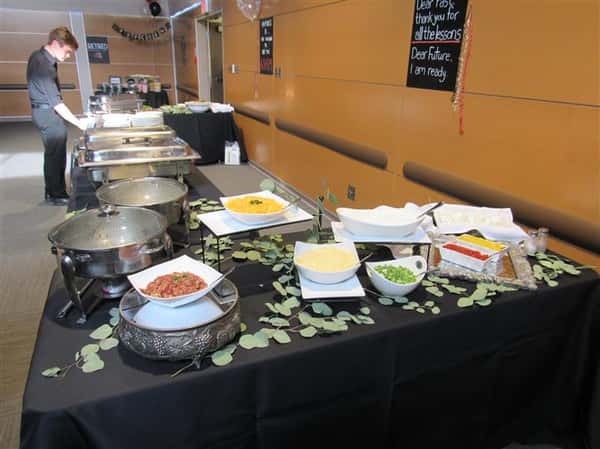 Buffet tables covered in linen with a variety of platters and catering equipment ready for service