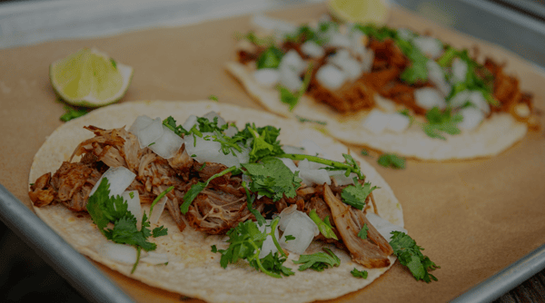 Authentic street tacos topped with slow-cooked shredded pork, fresh cilantro, diced onions, and lime wedges, served fresh at Burrito Famous.