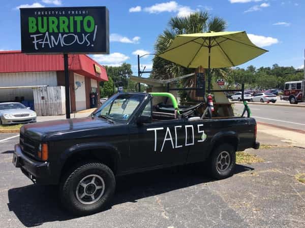 Burrito Famous taco truck parked outside the restaurant, featuring a custom pickup truck with outdoor seating and the Burrito Famous roadside sign.