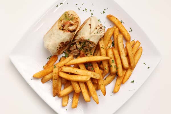 A plate of Nashville hot chicken and fries. The chicken is served in a wrap and garnished with parsley.