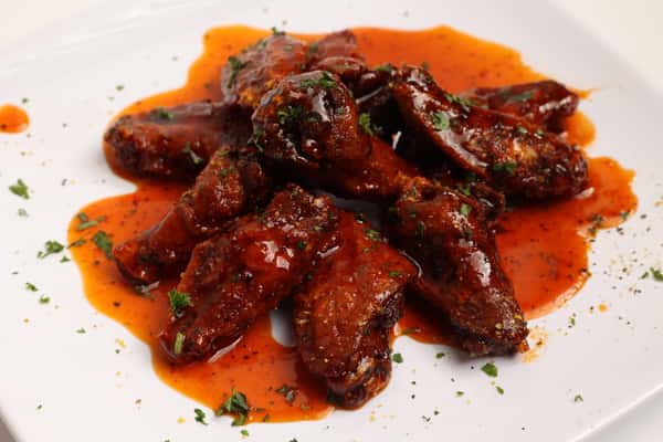 These are delicious chicken wings. The wings are coated in a vibrant red sauce and garnished with fresh parsley.