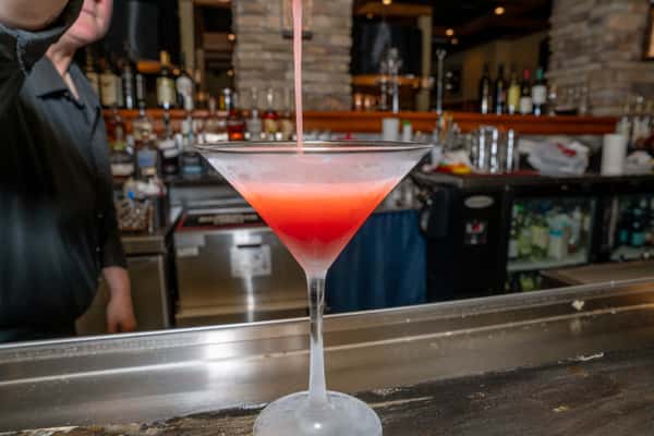 A cocktail being poured into a glass