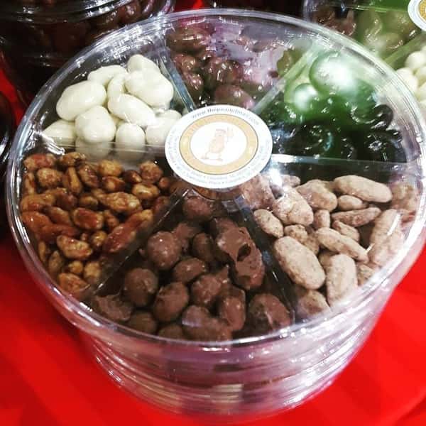 Various chocolate and candied nuts in plastic container.