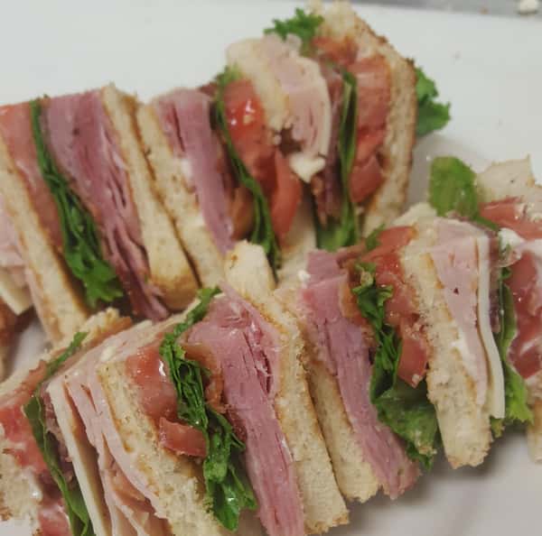 Classic Club sandwiches. Triple decker with shaved ham, smoked turkey, white american cheese, applewood bacon, mayo, green leaf lettuce, and vine ripe tomato.