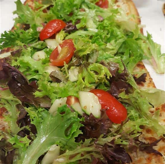 Veggie flatbread. Garlic spread and mozzarella baked crisp topped with a tossed salad with cucumber, grape tomato, red onion, mixed greens and italian dressing.