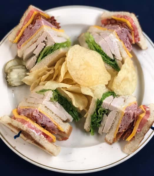 Turkey club sandwich with lettuce, cheese, ham, bacon and cheddar cheese with potato chips