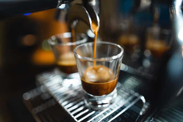 Espresso shot pouring from a machine into a clear glass