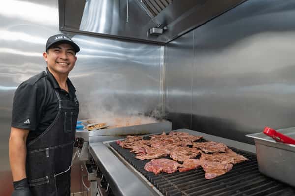 Cook grilling meat in the kitchen