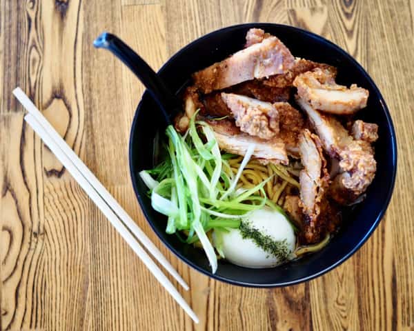 Bowl of ramen with crispy fried chicken, scallions, and soft-boiled egg, served with chopsticks