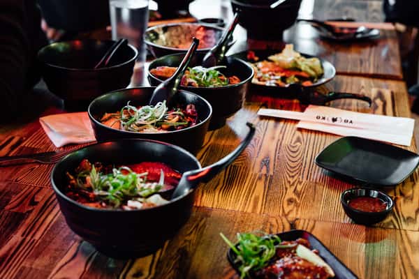 Multiple bowls of ramen with green onions on a long wooden table