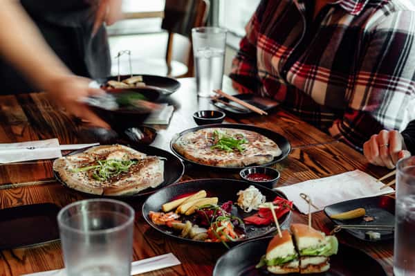 Assorted Japanese appetizers and burger on a wooden table with diners