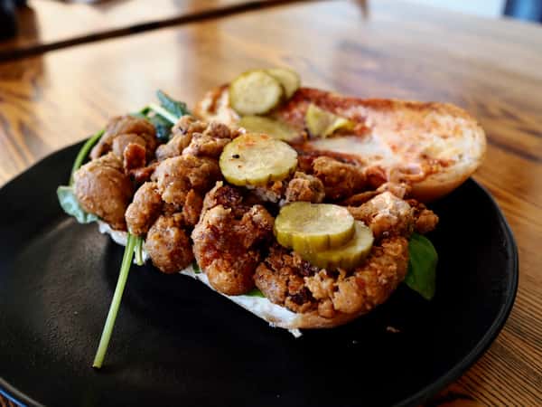 Fried chicken sandwich with pickles and greens on a toasted bun