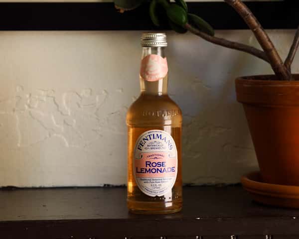 Bottle of Fentimans Rose Lemonade placed on a shelf next to a potted plant