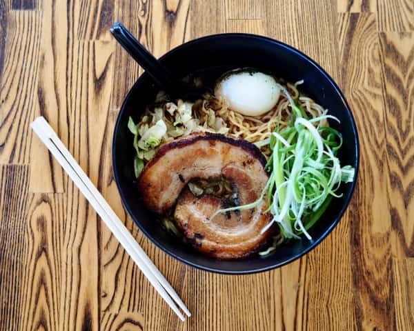 Bowl of ramen with pork belly, soft-boiled egg, cabbage, scallions, and chopsticks