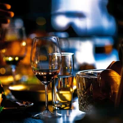 Elegant bar scene with wine and whiskey glasses, dim moody lighting, and a warm, intimate atmosphere.
