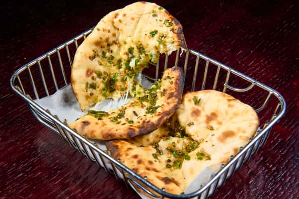 Garlic naan bread with herbs and melted butter in a serving basket