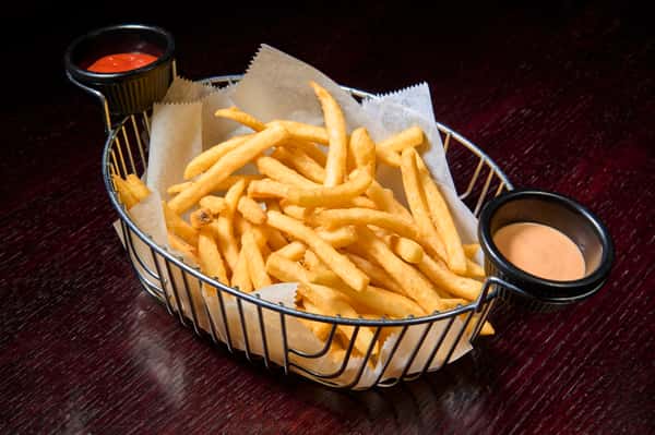 crispy golden french fries served in a metal basket with ketchup and creamy dipping sauce