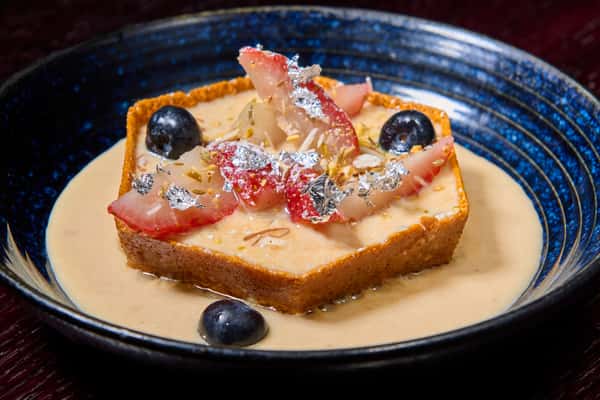Rasmalai tres leches cake topped with fresh fruit and edible silver leaf
