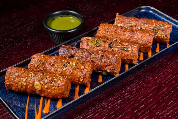 Spiced grilled kebabs served on a platter with dipping sauce