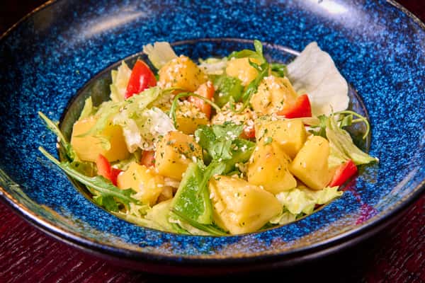 Tropical fruit salad with pineapple, greens, and light dressing