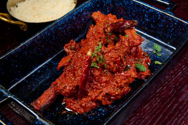 Spicy red curry lamb chops garnished with herbs and dried chilies