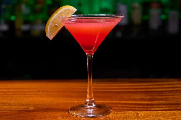Red cocktail martini with lemon garnish served at a bar