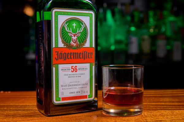 Jägermeister bottle with a glass of herbal liqueur on a bar counter