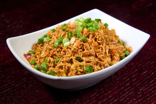 Vegetable fried rice garnished with green onions in a white bowl