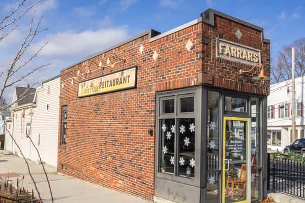 Brick corner building with Farrar's Delite Rose Restaurant signage, large windows, and a yellow-trimmed entrance on a sunny street.