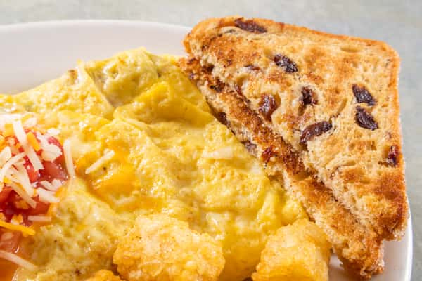 Cheese omelet topped with salsa and shredded cheese, served with crispy tater tots and toasted raisin bread.