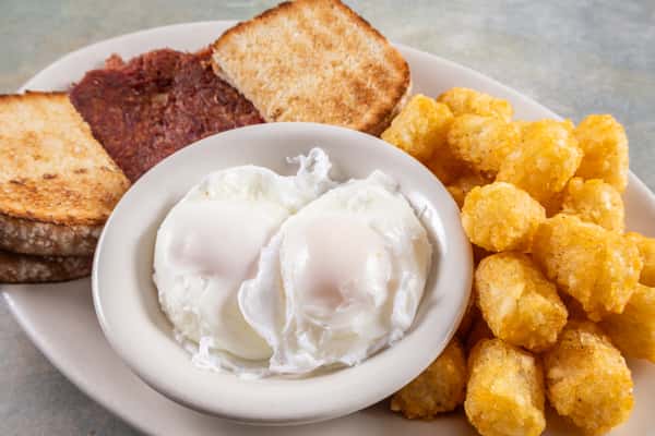 Breakfast plate with poached eggs, crispy tater tots, toasted bread, and a slice of corned beef hash.