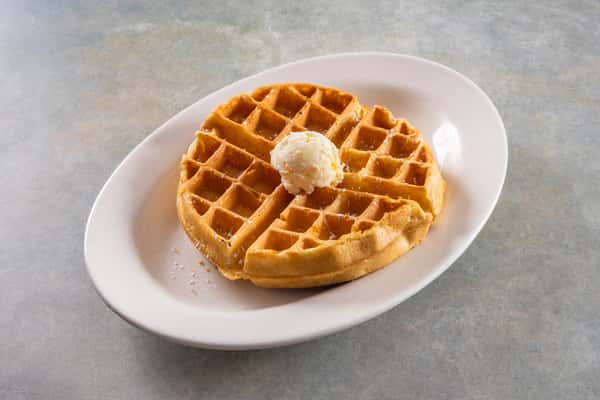 This image shows a classic golden waffle served with a scoop of butter on top and a light dusting of powdered sugar — a simple, traditional breakfast option.