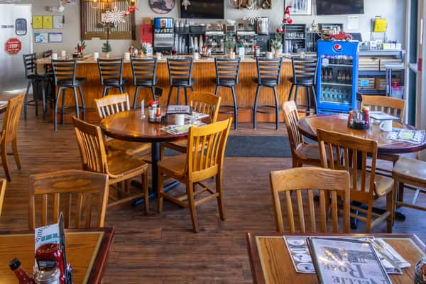A welcoming diner interior with wood furnishings, bar seating, and cheerful holiday decorations like snowflakes and garlands.